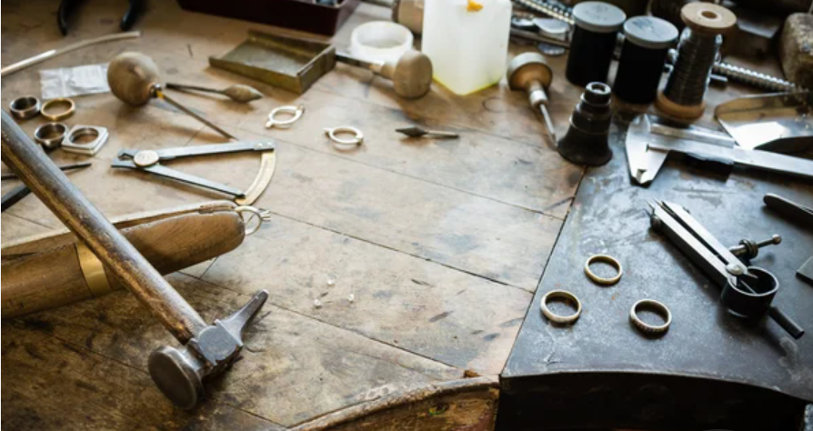 a jeweler's bench with tools and unfinished jewelry