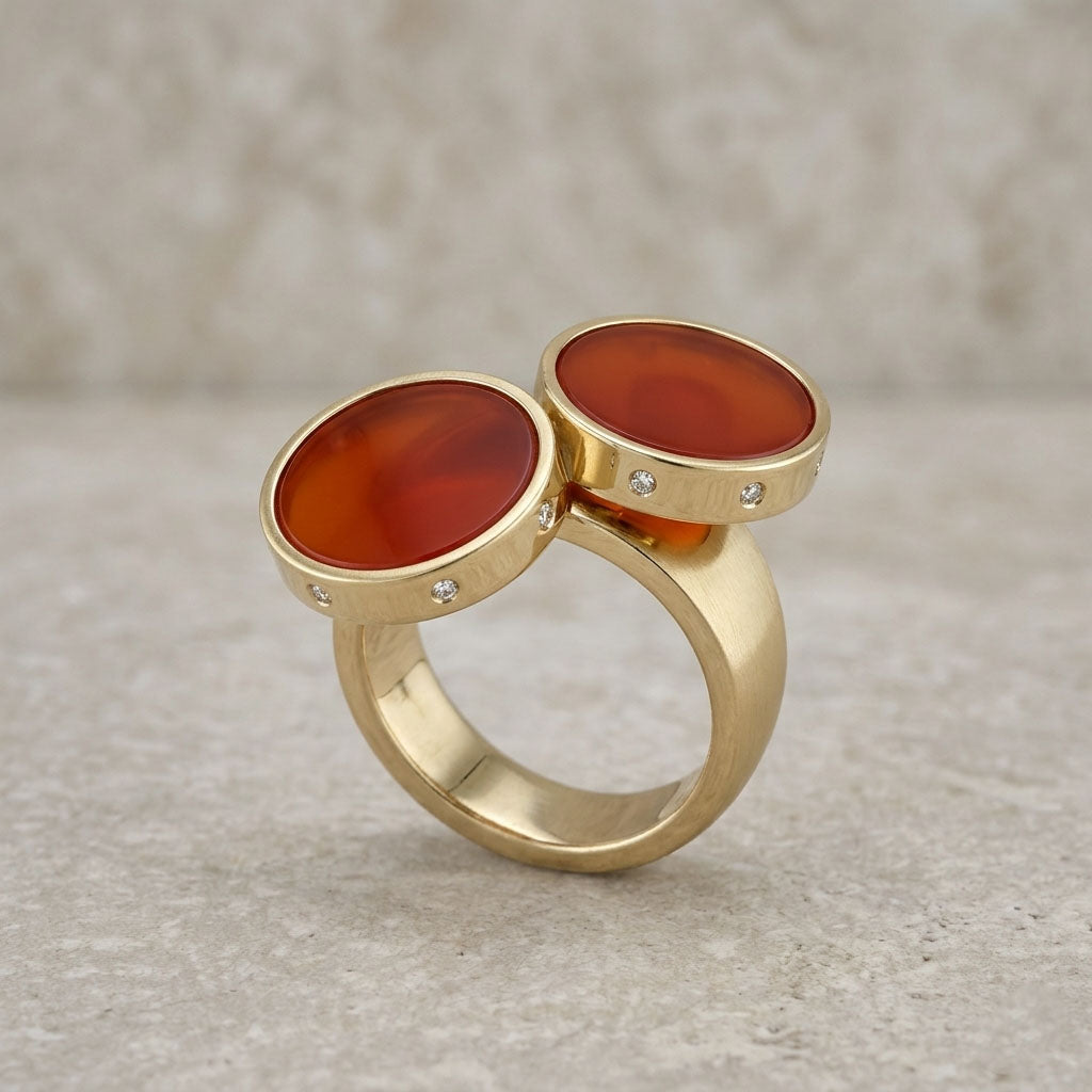 Gold ring with two red stones on a beige background