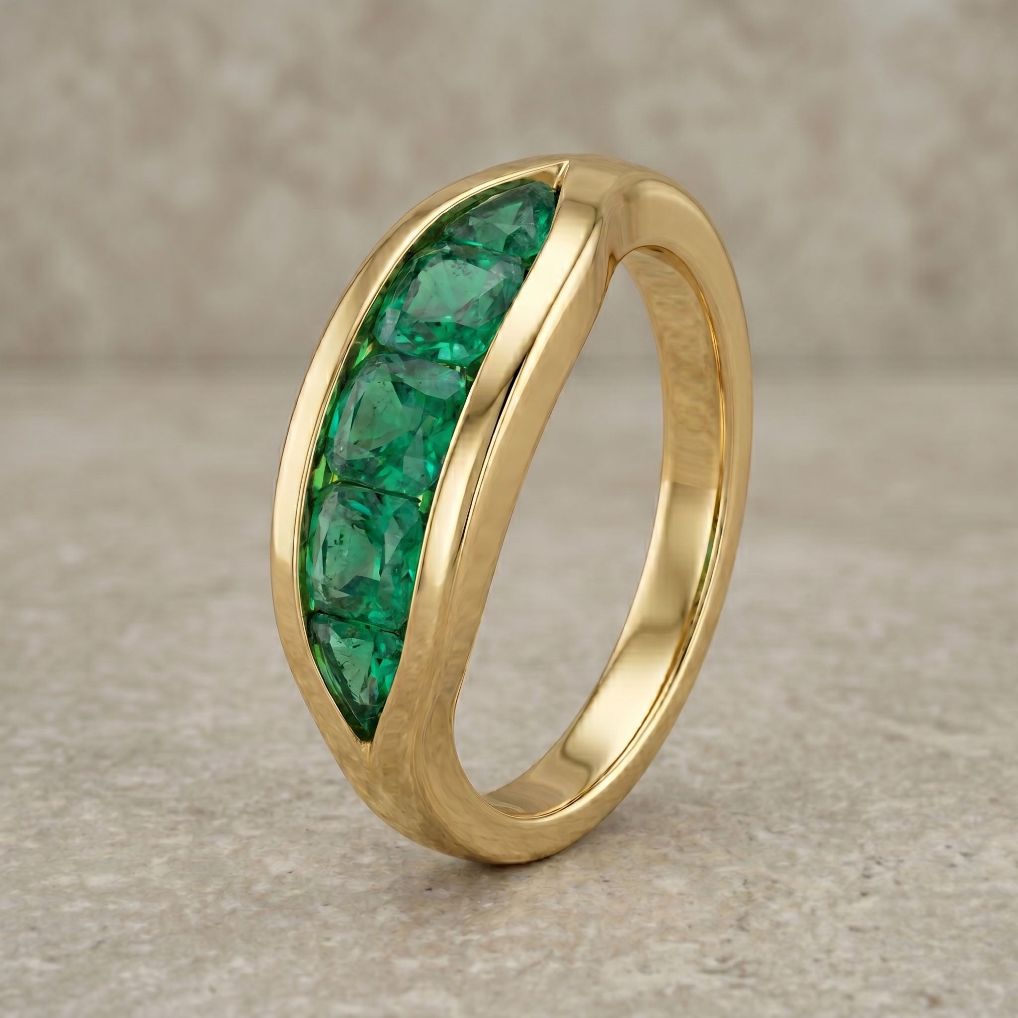 Gold ring with green gemstones on a textured beige background