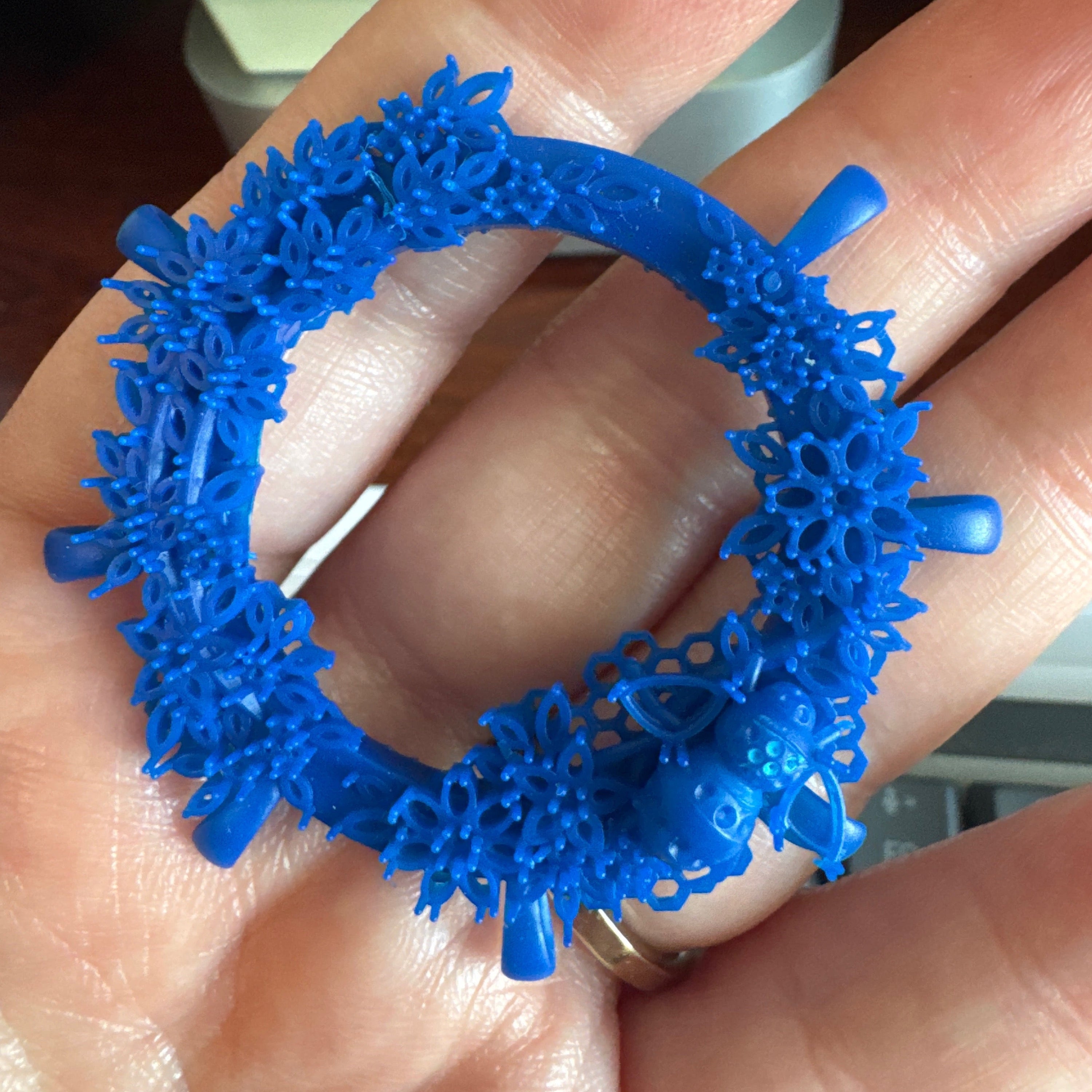 Blue textured ring held in a hand with a blurred background