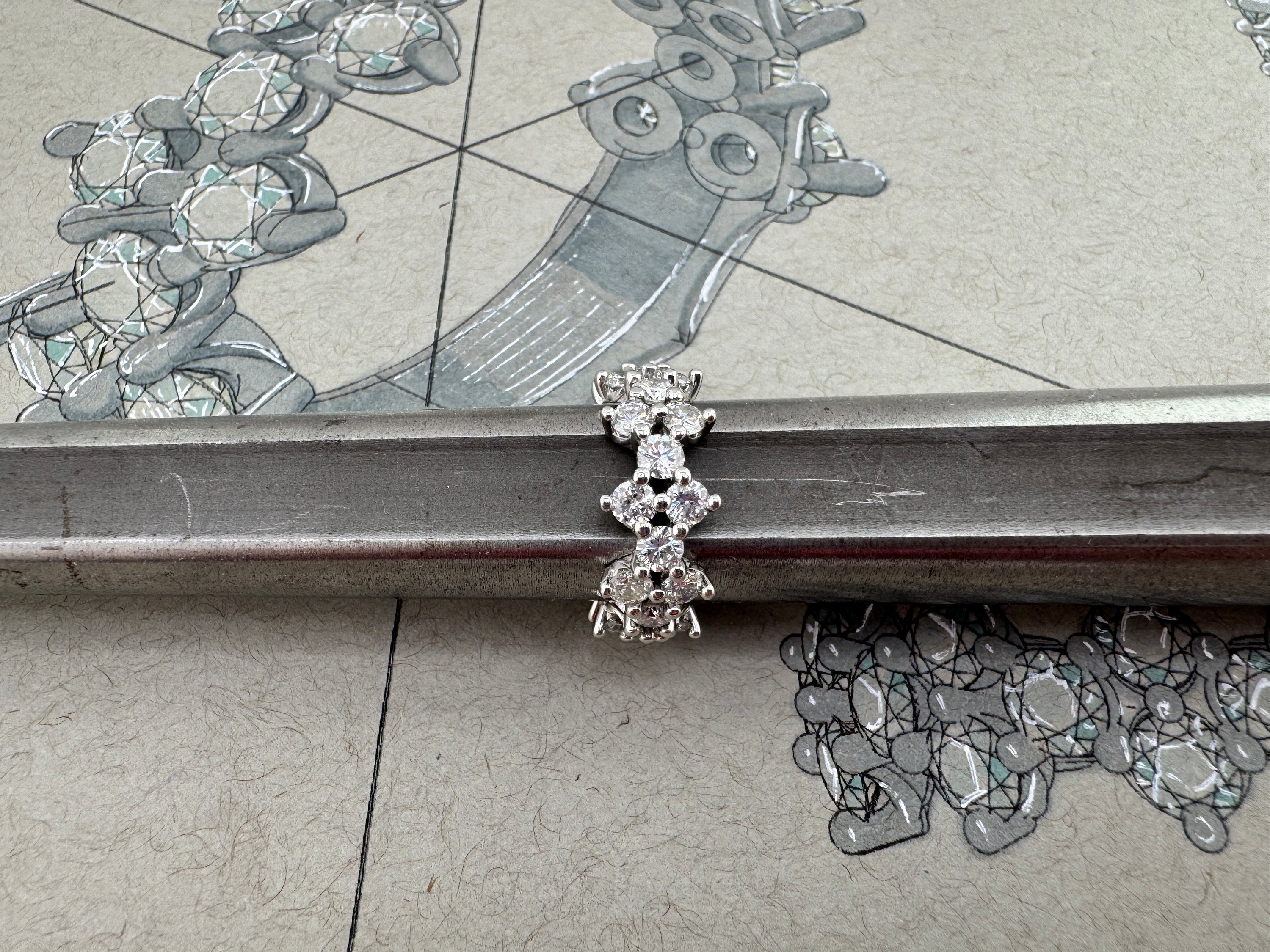 Diamond ring on a mandrel atop a sketched jewelry design