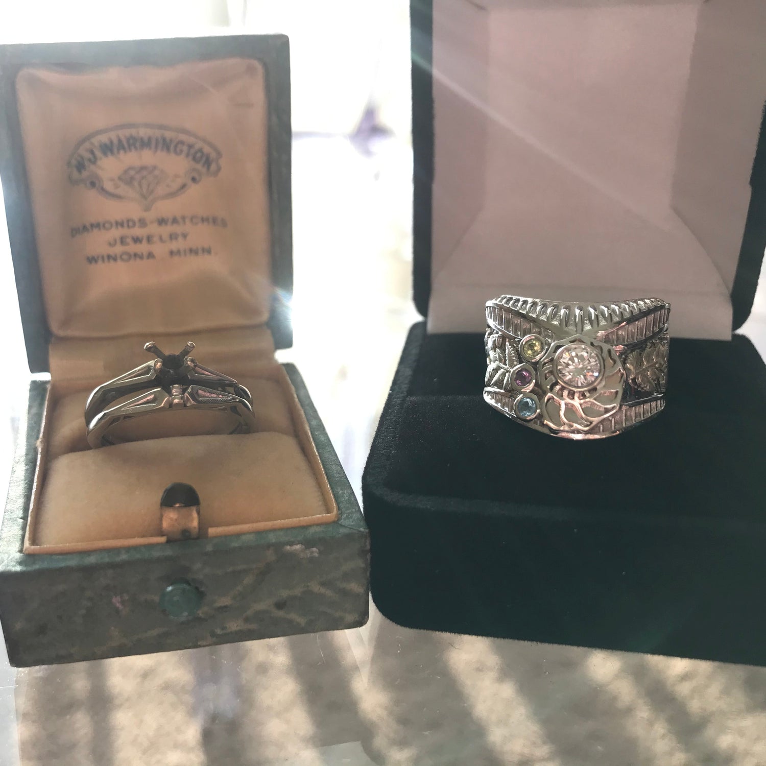 Two silver rings in open jewelry boxes with visible branding.