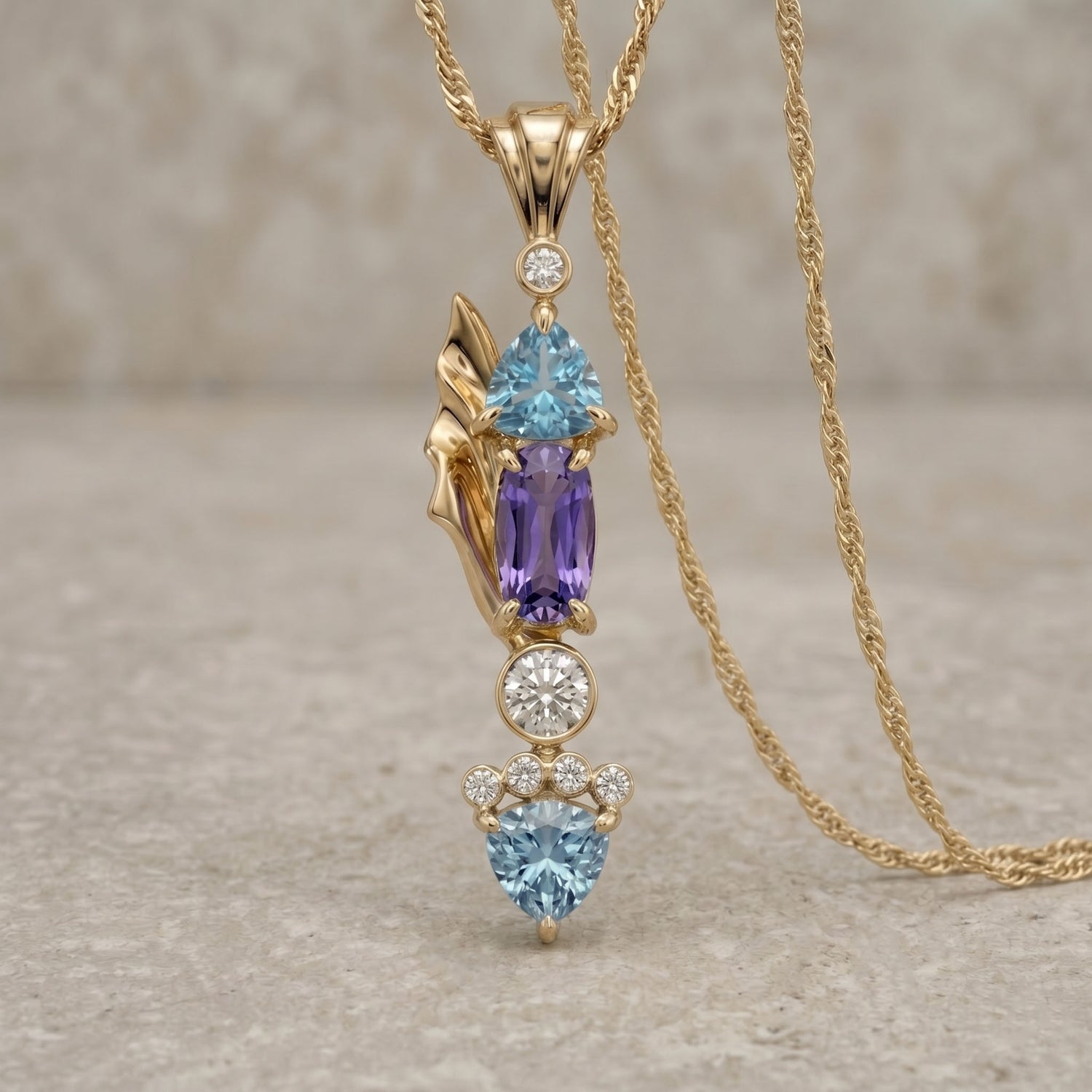 Gold necklace with gemstone pendant on a textured surface